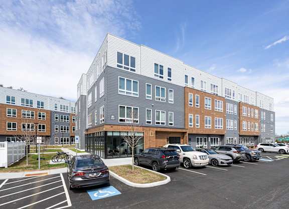 A parking lot with a building in the background and a car with a handicap sign at Seacoast Residences Apartments, Oakland, ME
