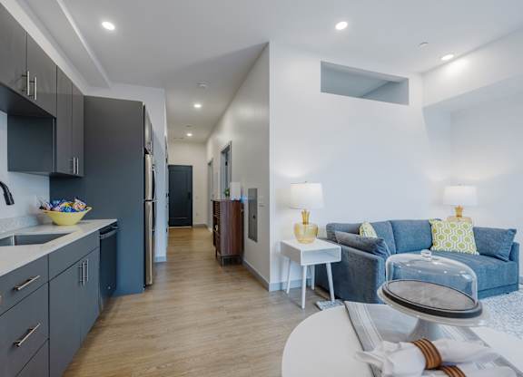 A modern kitchen with a blue couch in the living room at Seacoast Residences Apartments, Oakland, Maine