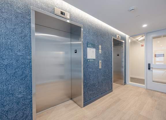A hallway with two elevators and a door on the right at Seacoast Residences Apartments, Oakland, Maine