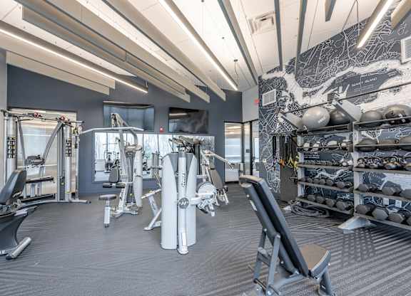 A gym with a variety of equipment including weights and machines at Seacoast Residences Apartments, Oakland