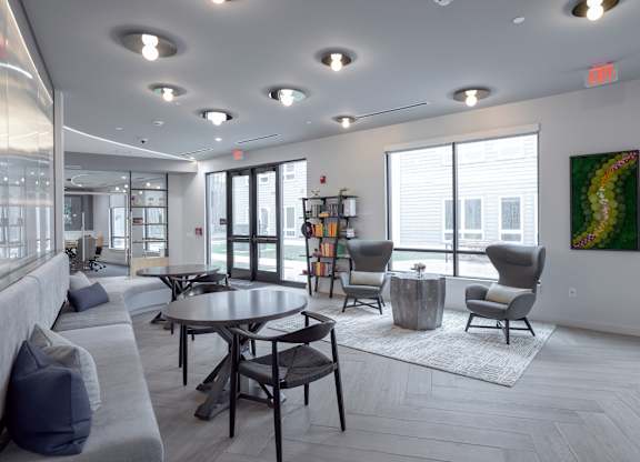 A modern living room with a grey sofa, a round table, and a painting on the wall at Seacoast Residences Apartments, Oakland, ME