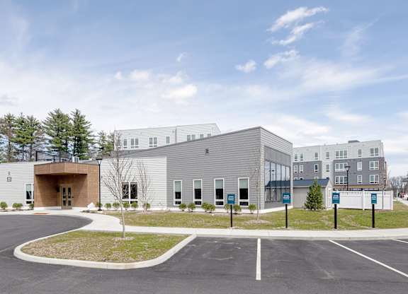 A modern building with a parking lot in front at Seacoast Residences Apartments, Oakland, Maine