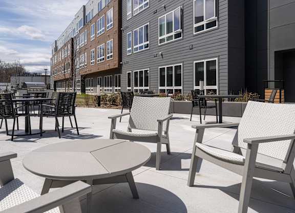 A patio with a table and chairs is in front of a building at Seacoast Residences Apartments, Maine