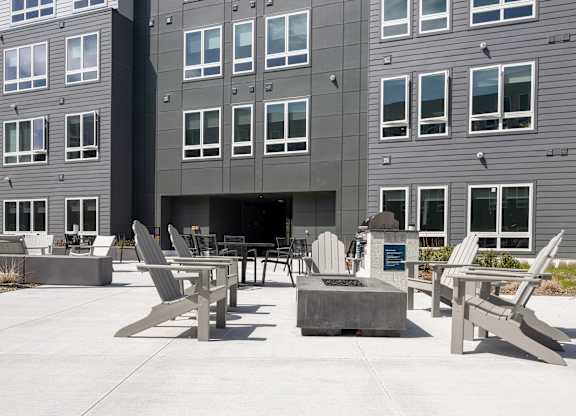 A grey building with a patio area in front at Seacoast Residences Apartments, Oakland