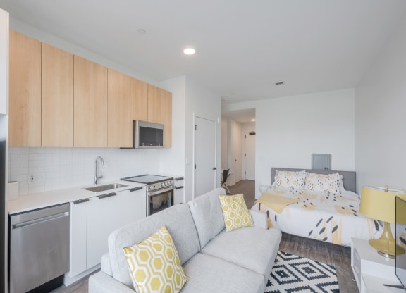 a living room with a couch and a kitchen and a bed