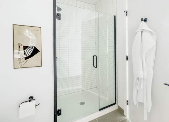 A white towel is hanging on a hook on a white wall.