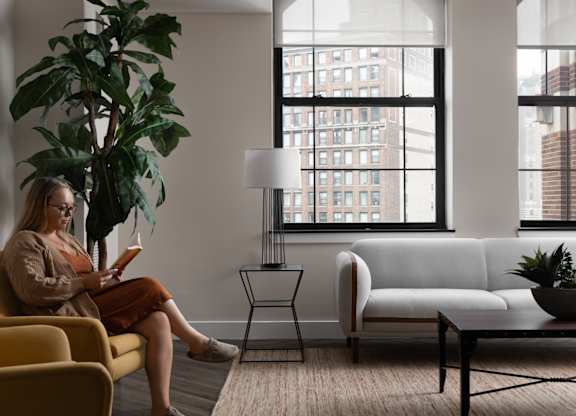a woman sitting on a couch in a living room reading a book