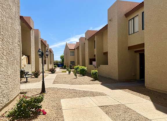 A sunny day in a courtyard surrounded by beige buildings.