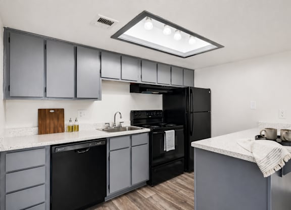 A modern kitchen with black appliances and grey cabinets.