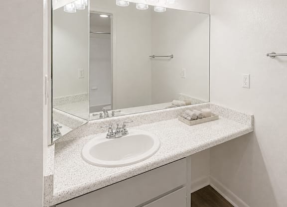 A bathroom with a sink, mirror, and lights.