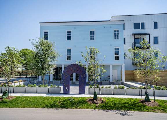 A white building with a purple arch in front of it.