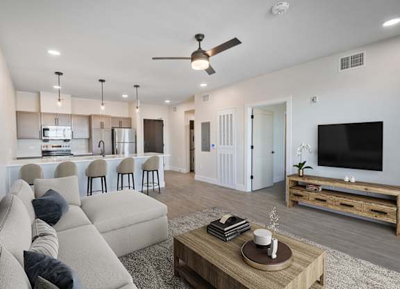A modern living room with a beige sofa, a wooden coffee table, and a flat-screen TV.