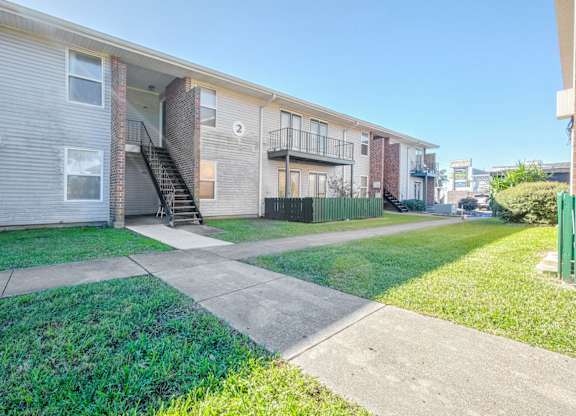 Apartment complex with a green fence and a clear sky.