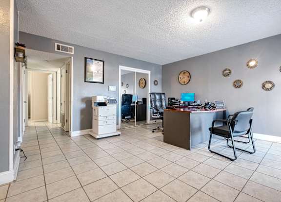 A room with a white tile floor and a brown table with a chair.