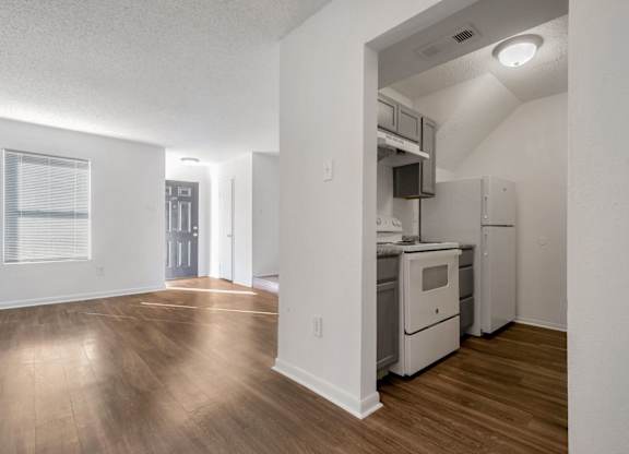 A kitchen with white appliances and wooden floors.