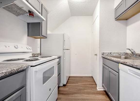 A kitchen with white appliances and a marble countertop.