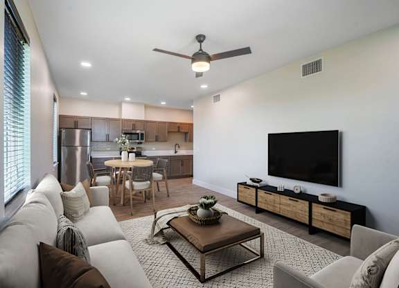 A modern living room with a flat screen TV and a kitchen area in the background.