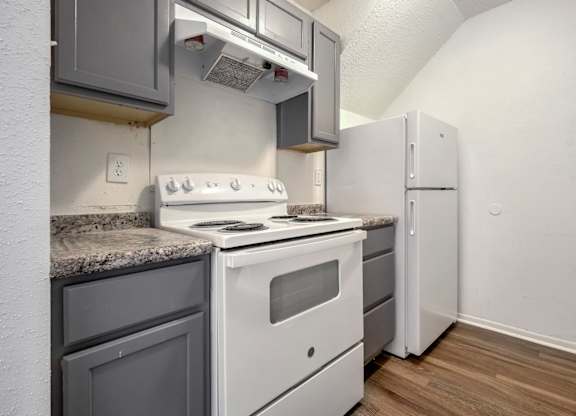A kitchen with a white stove and grey cabinets.