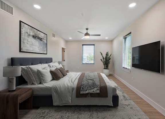 A bedroom with a large bed and a flat screen TV mounted on the wall.