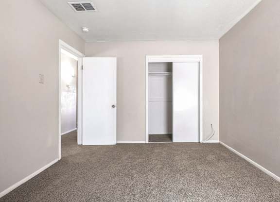 A room with two white doors and a carpeted floor.