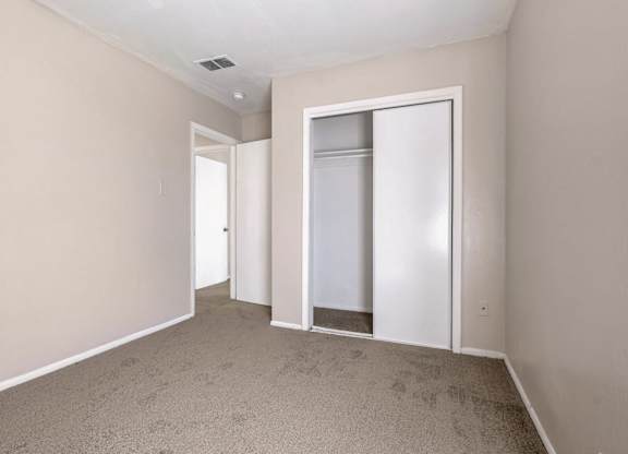 A room with a white door and a carpeted floor.