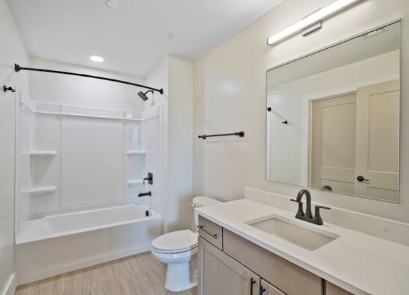 A white bathroom with a toilet, sink, and bathtub.
