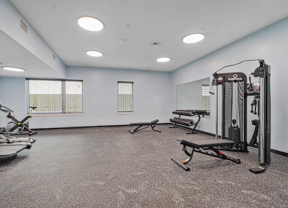 A spacious gym with a variety of equipment including treadmills, elliptical machines, and weight machines.