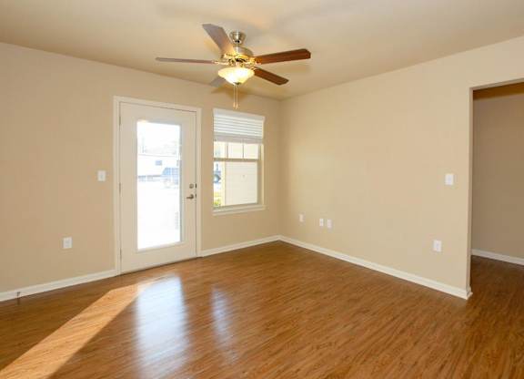 A room with a ceiling fan and wooden flooring.