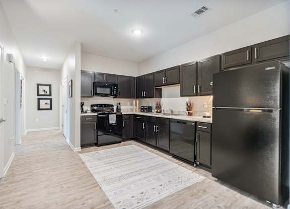 A kitchen with black appliances and wooden floors.