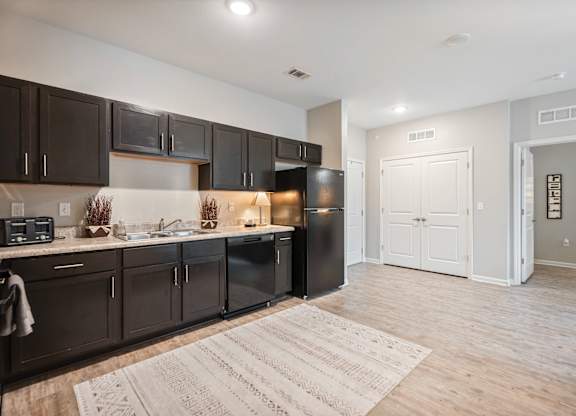 A kitchen with dark brown cabinets and a black refrigerator.