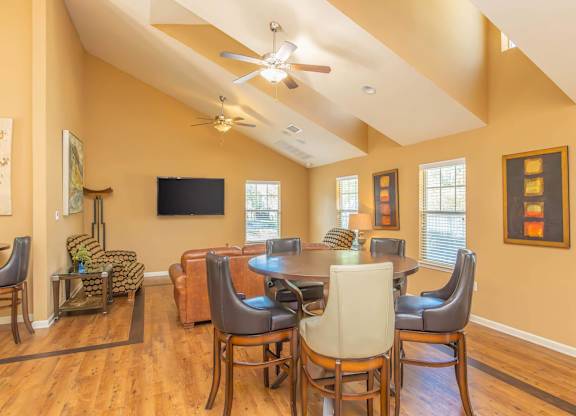 A living room with a television and a dining table with chairs.