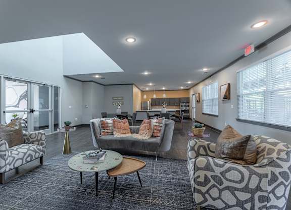 A spacious waiting room with grey couches and pillows.