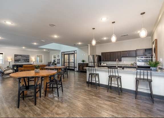 A modern kitchen with a dining table and bar stools.