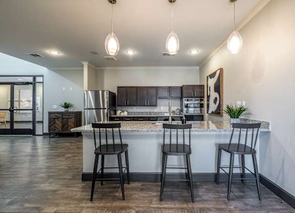 A modern kitchen with a bar area and two stools.