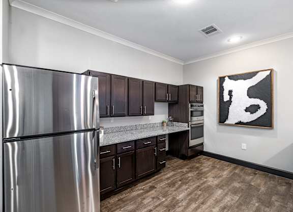 A modern kitchen with a stainless steel refrigerator and wooden floors.
