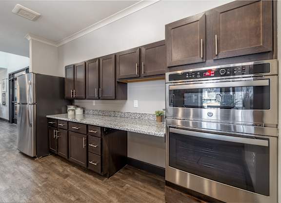 A modern kitchen with dark brown cabinets and stainless steel appliances.