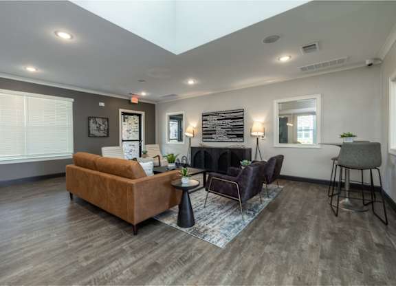 A living room with a brown couch, a black chair, and a rug.