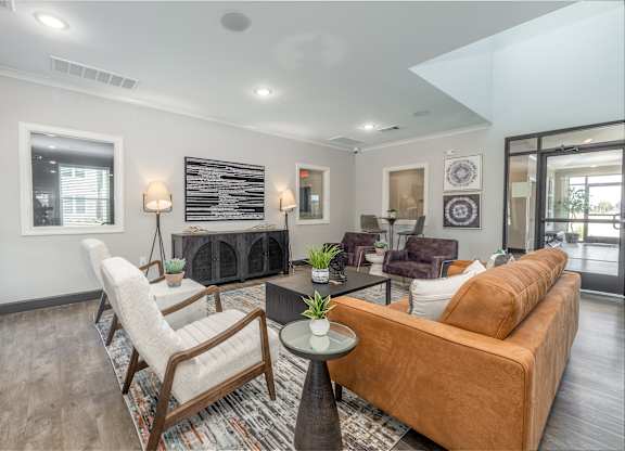 A living room with a brown couch, a chair, and a table with a plant on it.