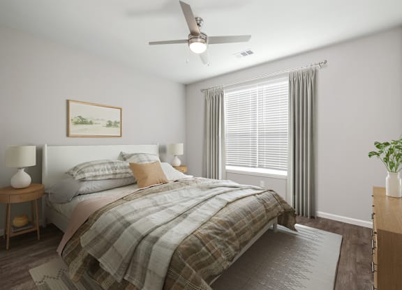 A bedroom with a bed, a ceiling fan, and a painting on the wall.