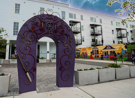 A purple archway with swirls and a key design is in the foreground of a building.