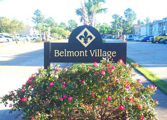 A sign for Belmont Village is surrounded by flowers.
