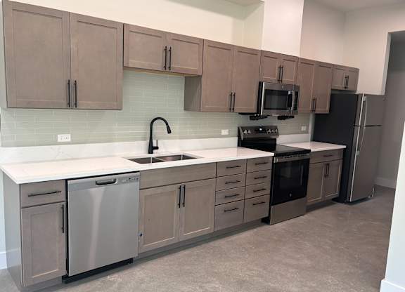 A kitchen with brown cabinets and a black fridge.