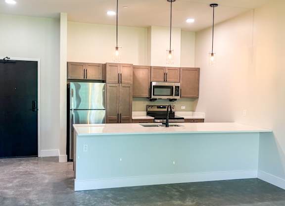 A kitchen with a black refrigerator, brown cabinets, and a white countertop.