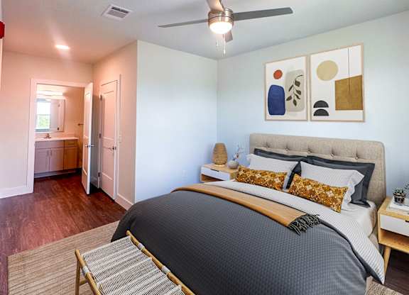 A bedroom with a bed, a bench, and a ceiling fan.