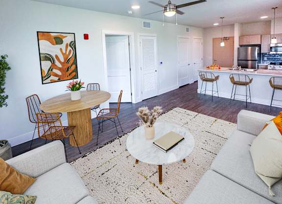 A living room with a white couch and a round table with a plant on it.
