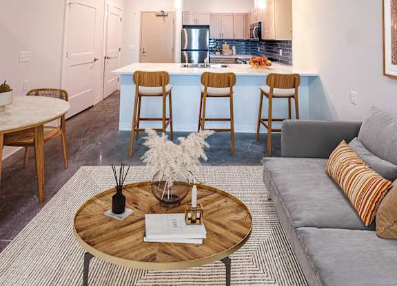 A modern kitchen with a bar stool and a grey sofa.