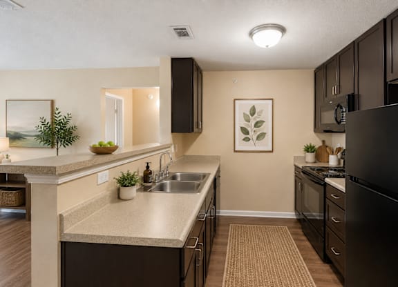 A kitchen with a black refrigerator and brown cabinets.