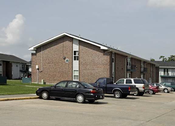 A black car is parked in front of a brick building.