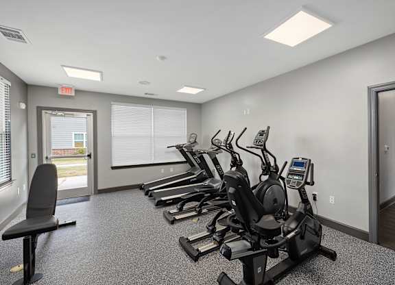A gym with a row of stationary bikes and a treadmill.