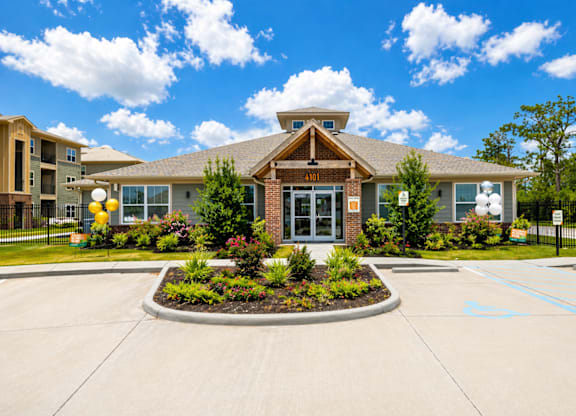 A building with a front yard and a parking lot in front.